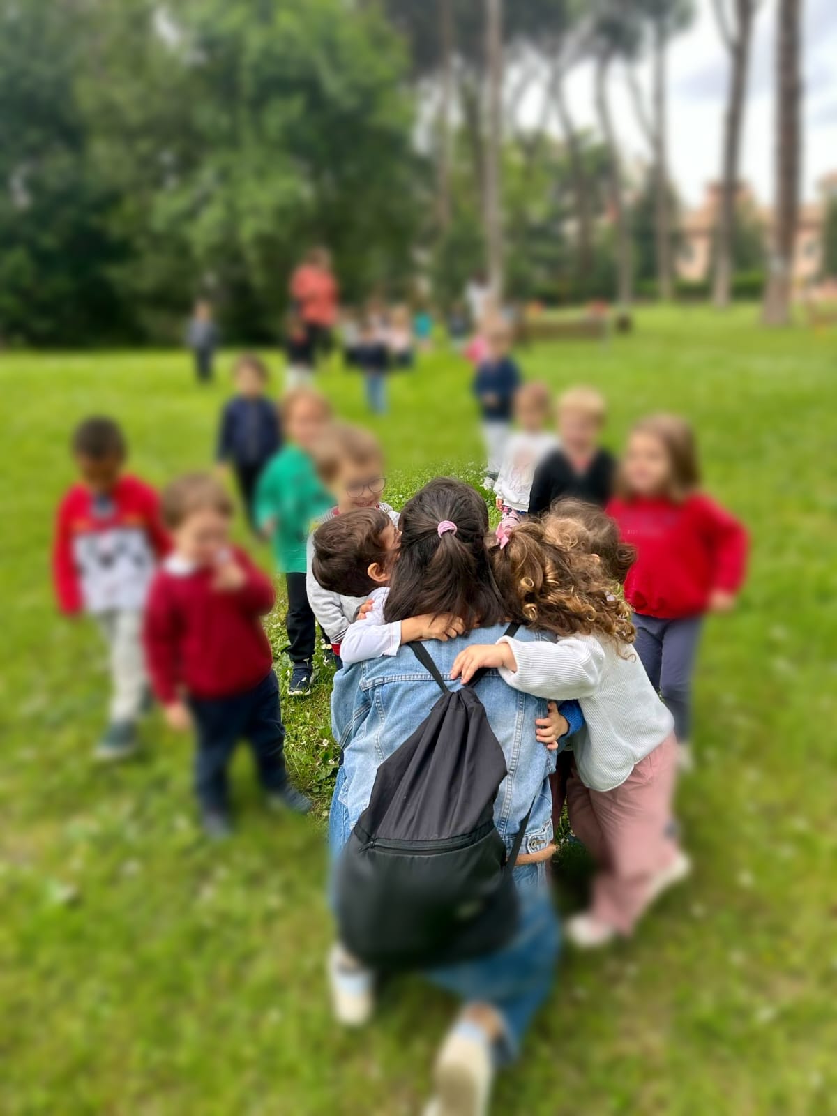 Abbraccio tra educatrice e bambini nel parco